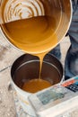 Preparator pours chemical components for epoxy resin floors from the tin bucket