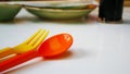 Prepare orange spoon and yellow fork for a kid.