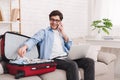 Prepare for travel. Man talking on phone and packing clothes Royalty Free Stock Photo