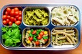 Prepared diet Lunches in lunch boxes: pasta, parmesan, lettuce, cherry tomatoes with basil.