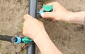 Prepared for early spring planting. Drip irrigation system close-up and hand screwing the fitting into the pipe. Royalty Free Stock Photo