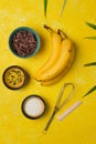 Prepared ingredients for cooking frozen chocolate covered bananas on a yellow concrete background. No-bake desserts