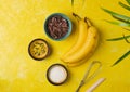 Prepared ingredients for cooking frozen chocolate covered bananas on a yellow concrete background. No-bake desserts