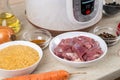 Prepared ingredients for cooking pilaf in modern multi cooker in kitchen on a table. Cooking pilau with meat in multicooker Royalty Free Stock Photo