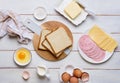 Prepared ingredients for making a hot croque madame sandwich on a white wooden background. Recipes for sandwiches, hot breakfasts