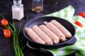 Prepared raw chicken or pork sausages in a cast-iron frying pan on a dark concrete background Royalty Free Stock Photo