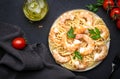 Prepared spaghetti pasta with shrimp, olive oil and parsley in plate on black table background. Top view