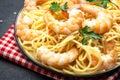 Prepared spaghetti pasta with shrimp, olive oil and parsley in plate on black table background. Top view