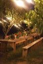 Prepared table for a rustic outdoor dinner at night with lamps Royalty Free Stock Photo