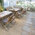 Prepared wooden tables and chairs with floral decorations and stone paved floor in indoor garden restaurant