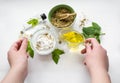 Preparing an alternative medicine, herbal extract: white background, hands hold a jar of oil over a bowl with white essence, and Royalty Free Stock Photo