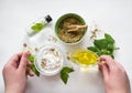 Preparing an alternative medicine, herbal extract: white background, hands hold a jar of oil over a bowl with white essence, and Royalty Free Stock Photo