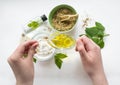 Preparing an alternative medicine, herbal extract: white background, hands hold a jar of oil over a bowl with white essence, and Royalty Free Stock Photo