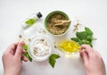 Preparing an alternative medicine, herbal extract: white background, hands hold a jar of oil over a bowl with white essence, and Royalty Free Stock Photo