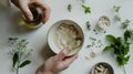 Preparing an alternative medicine, herbal extract: white background, hands hold a jar of oil over a bowl with white essence, and Royalty Free Stock Photo