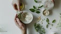 Preparing an alternative medicine, herbal extract: white background, hands hold a jar of oil over a bowl with white essence, and Royalty Free Stock Photo