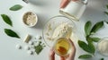 Preparing an alternative medicine, herbal extract: white background, hands hold a jar of oil over a bowl with white essence, and Royalty Free Stock Photo