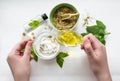 Preparing an alternative medicine, herbal extract: white background, hands hold a jar of oil over a bowl with white essence Royalty Free Stock Photo