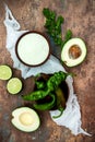 Preparing avocado cilantro sauce for fish tacos. Lime crema in a bowl on vintage stone background.