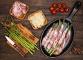 Preparing bacon wrapped asparagus on wooden table.  Cooking asparagus. Ingredients for cooking on wooden background Royalty Free Stock Photo