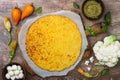 Preparing cauliflower pizza crust with pesto, yellow tomatoes, zucchini, mozzarella cheese and squash blossom