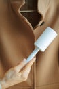 Closeup on woman cleaning coat with lint roller