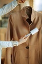 Closeup on woman cleaning coat on hanger with lint roller