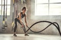 Preparing for the competition. Young athletic woman with perfect body doing crossfit exercises with a rope in the gym. Royalty Free Stock Photo