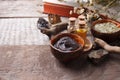 Preparing cosmetic black mud mask in ceramic bowl on vintage wooden background. Front view of facial clay emulsion on table