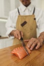 Preparing delicious rolling sushi in restaurant. Asian master slicing salmon fish Royalty Free Stock Photo