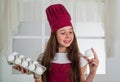 Preparing from eggs. happy child wear cook uniform. chef girl in hat and apron. kid cooking food in kitchen. choosing a Royalty Free Stock Photo