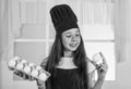 preparing from eggs. happy child wear cook uniform. chef girl in hat and apron. kid cooking food in kitchen. choosing a Royalty Free Stock Photo