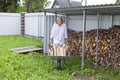 Preparing firewood for the cold season. A woman provides herself with heat in the house. A woman carries firewood from a