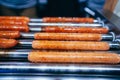 Preparing the French hot dog. Spinning sausages on the grill Royalty Free Stock Photo