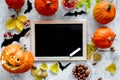 Preparing for halloween. Pumpkin head near pumpkins and black desk for notes on grey background top view mockup