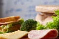 Preparing ham sandwiches for scool lunchbox on wooden background, close up.