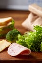 Preparing ham sandwiches for scool lunchbox on wooden background, close up.