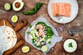 Preparing healthy lunch snacks. Fish tacos with grilled salmon, red onion, fresh salad leaves and avocado cilantro sauce