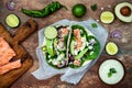 Preparing healthy lunch snacks. Fish tacos with grilled salmon, red onion, fresh salad leaves and avocado cilantro sauce Royalty Free Stock Photo