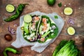 Preparing healthy lunch snacks. Fish tacos with grilled salmon, red onion, fresh salad leaves and avocado cilantro sauce