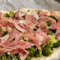 Preparing homemade pizza with vegetables and raw ham