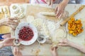 Preparing of homemade sweet dumplings with fruits, home dinner cooking, hands of family members, real life style. Top view Royalty Free Stock Photo