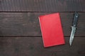 Preparing for hunting concept. Red notebook and hunting knife on a dark wooden table background. Flat lay
