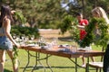 Preparing for an open-air party. Girls decorators decoration with fresh flowers on served tables. Decoration Details