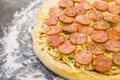 Preparing pepperoni pizza on black granite table