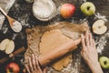 Preparing pie crust for apple pie. Hands rolling dough with rolling pin on the wooden background Royalty Free Stock Photo