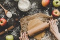 Preparing pie crust for apple pie. Hands rolling dough with rolling pin on the wooden background Royalty Free Stock Photo