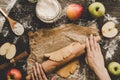 Preparing pie crust for apple pie. Hands rolling dough with rolling pin on the wooden table Royalty Free Stock Photo