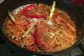 Preparing pilaf in a cauldron, process of cooking. Bright red chilly pepper, carrot, garlic merged and boiled in fat liquid.