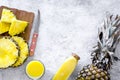 Preparing pineapple juice. Bottle with beverage near fruit slices and knife on grey background top view copyspace Royalty Free Stock Photo